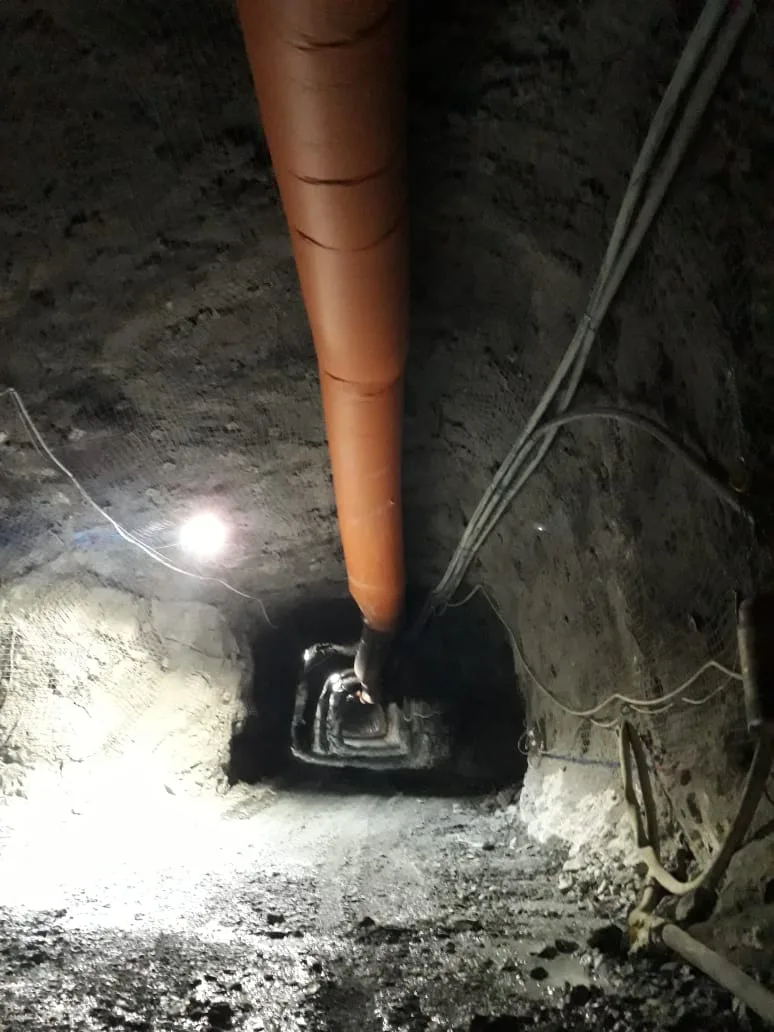 Manga impelente de ventilación azul recorriendo el techo de una galería minera subterránea, fotografía industrial realista